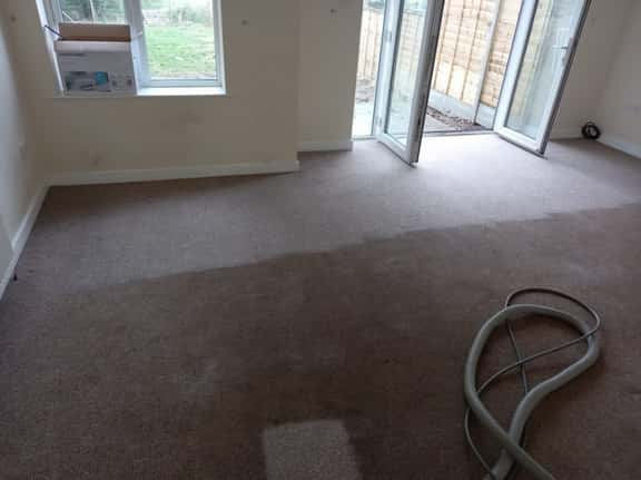 This is a photo of an empty living room with a brown carpet that is in the process of having its carpets steam cleaned works carried out by Herne Hill Carpet Cleaning.